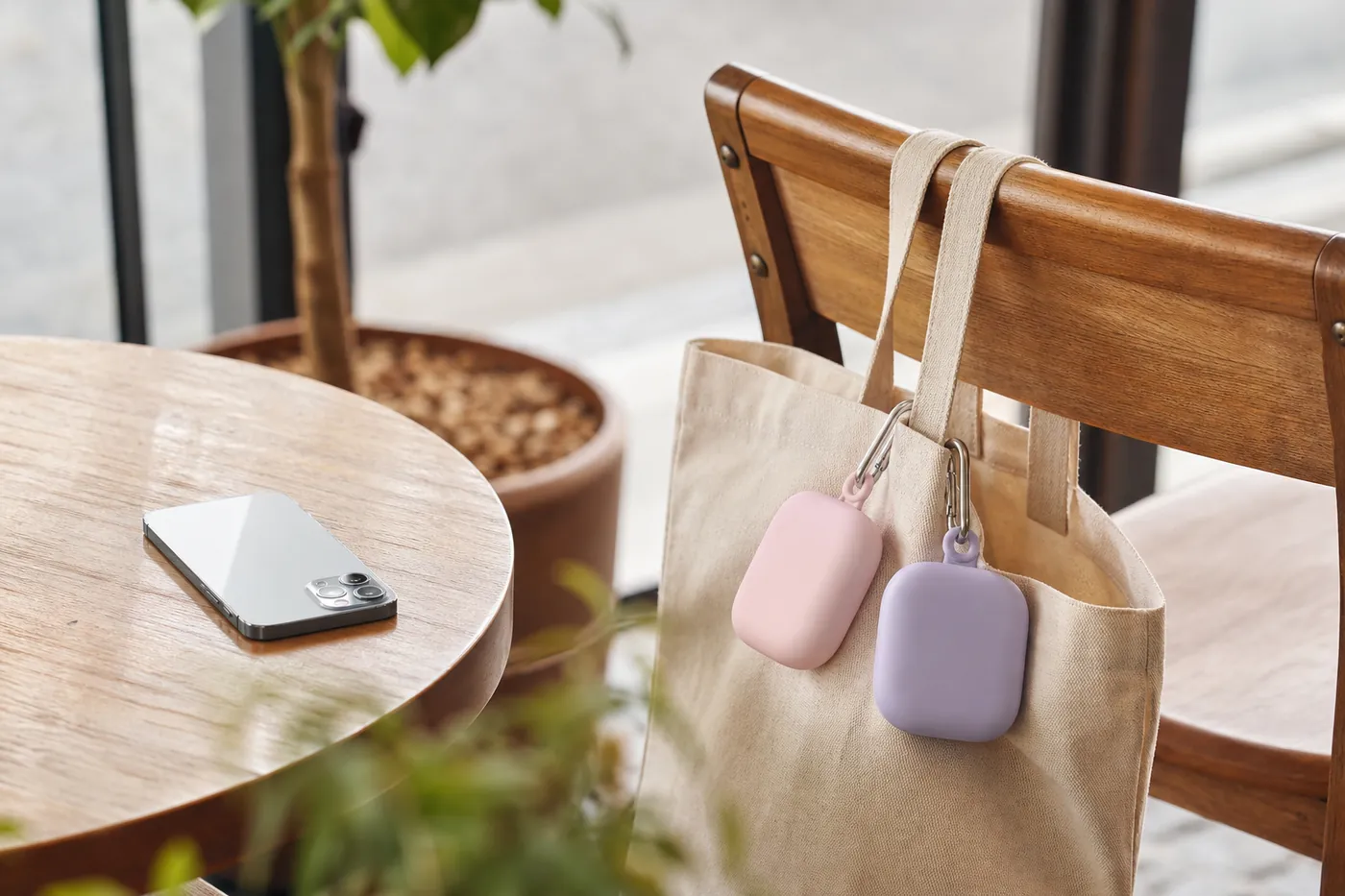 カフェの椅子に掛けたトートバッグに、丸いパステルカラーのモバイルバッテリーが2つカラビナで下がっているイメージ