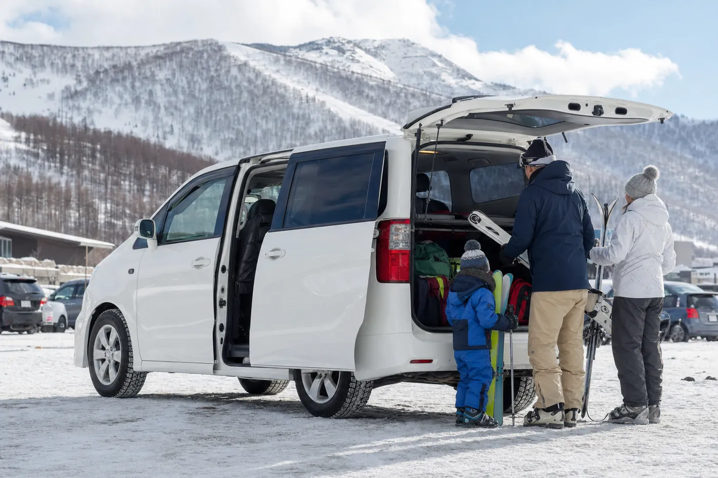 雪のスキー場の駐車場で、白い大型ミニバンに家族がスキー道具を積み込んでいるイメージ(AI生成)